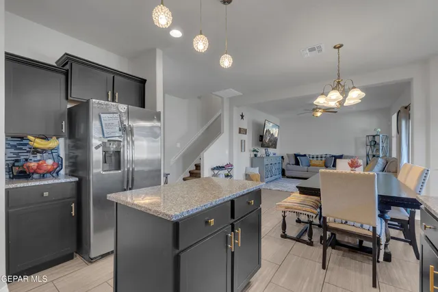 a kitchen with stainless steel appliances granite countertop a refrigerator a sink dishwasher a stove and a dining table with wooden floor