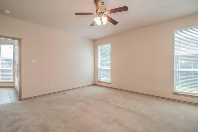 an empty room with windows and fan