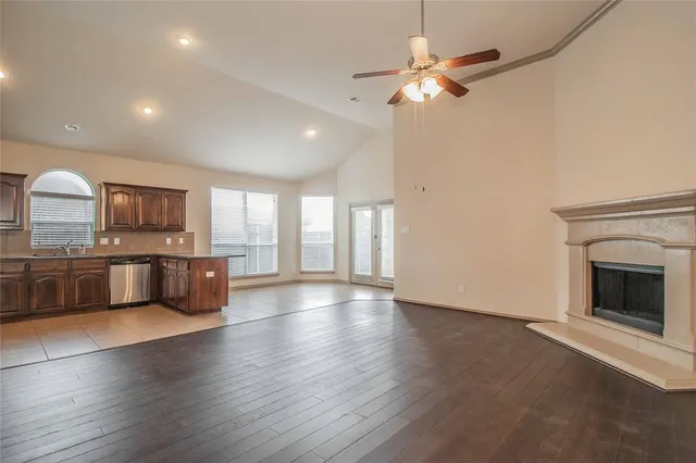 a view of an empty room with a kitchen and wooden floor