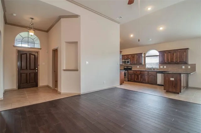 a view of a kitchen with stainless steel appliances granite countertop a refrigerator and a wooden floors