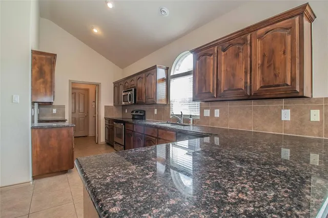 a kitchen with granite countertop a refrigerator and a stove top oven