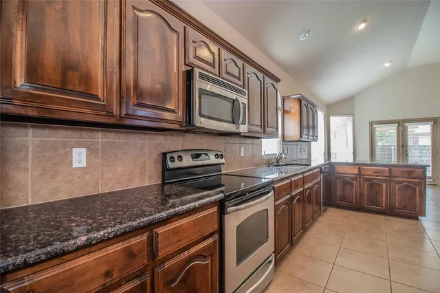 a kitchen with stainless steel appliances granite countertop a stove a sink and a microwave