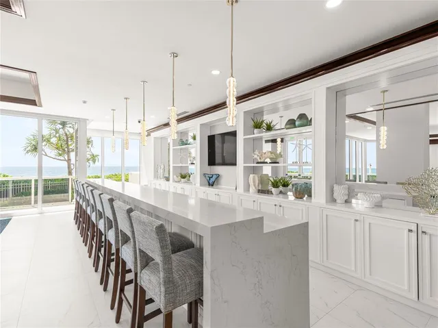 a large white kitchen with lots of counter space and chandelier