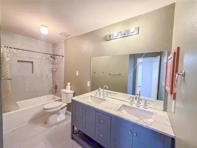 a bathroom with a double vanity sink toilet mirror and shower