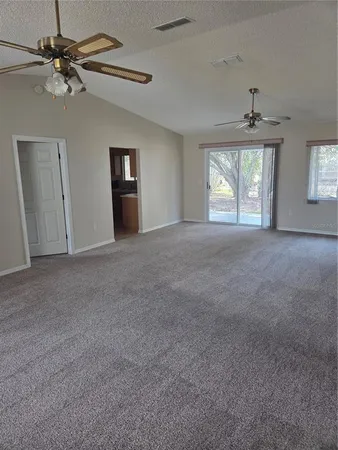 en empty room with windows and ceiling fan