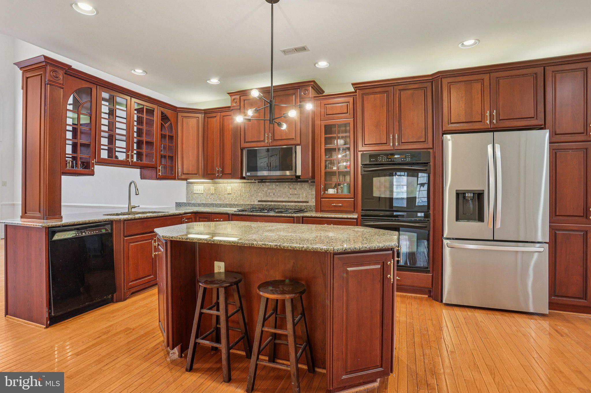 82 Granville Way Exton, PA 19341 - Photo 14 of 51 a kitchen with kitchen island granite countertop wooden floors white cabinets and stainless steel appliances