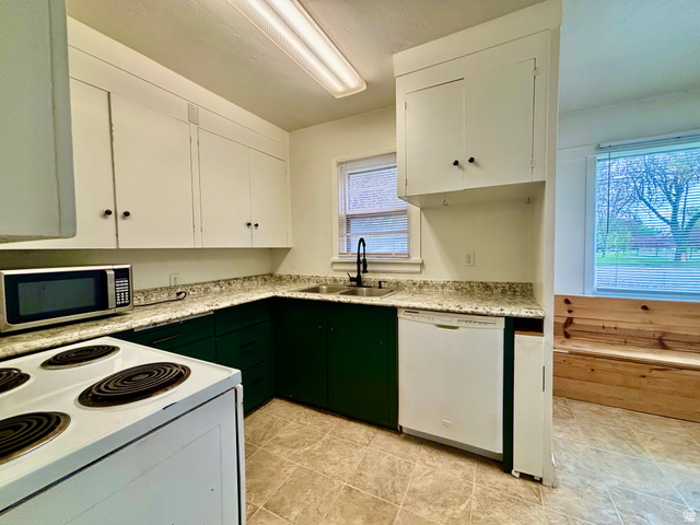 704 North 200 East Logan, UT 84321 - Photo 7 of 24 Two tone kitchen featuring white appliances, two tone cabinetry, and light stone counters