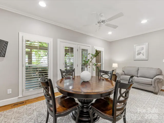 a kitchen with stainless steel appliances granite countertop a stove top oven a sink a dining table and chairs with wooden floor