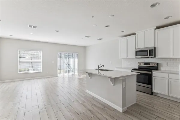 a kitchen with stainless steel appliances wooden floors and white cabinets