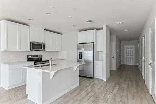 a kitchen with stainless steel appliances granite countertop a refrigerator oven a sink dishwasher and white cabinets with wooden floor