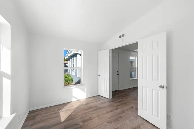 a view of an empty room with wooden floor and a window