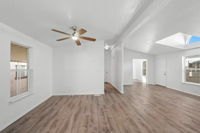 a view of an empty room with window and wooden floor