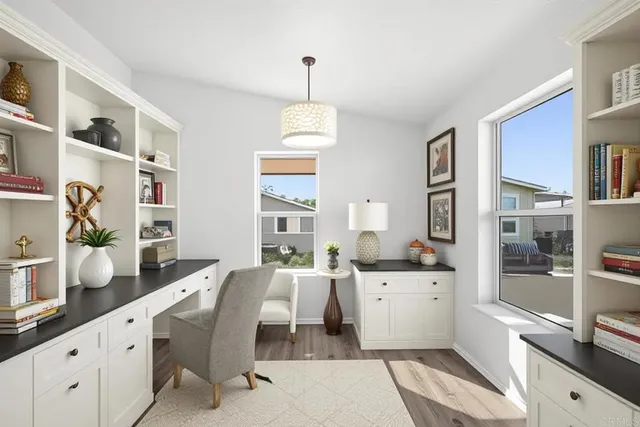 a living room with stainless steel appliances furniture a rug a clock and a window