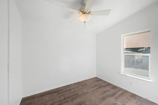 an empty room with a window and a fan