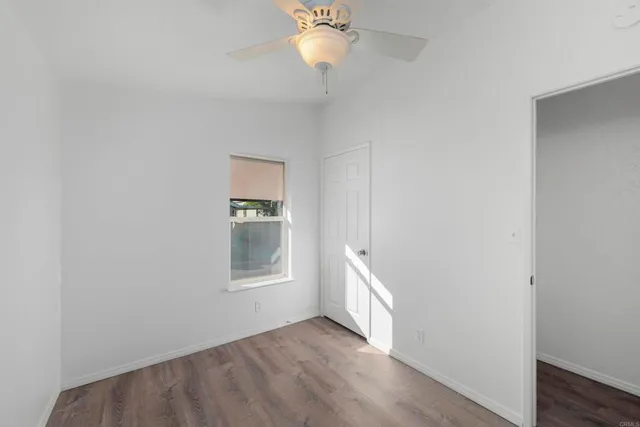 an empty room with a window and chandelier fan