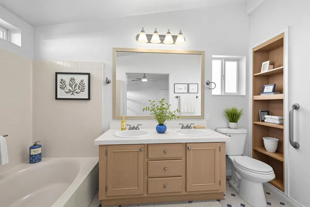a bathroom with a toilet a sink a large mirror and vanity