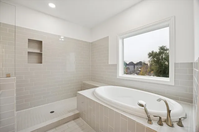 a bathroom with a tub a window and a shower