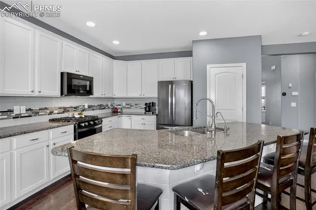 a kitchen with kitchen island granite countertop a table chairs microwave and refrigerator