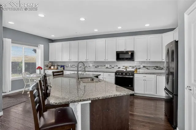 a kitchen with a refrigerator a stove a sink dishwasher with a dining table and chairs