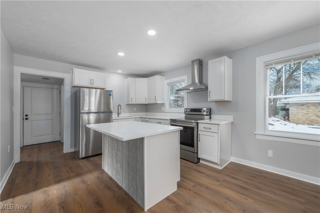 218 Roxboro Road Vermilion, OH 44089 - Photo 12 of 50 Kitchen featuring stainless steel appliances, white cabinetry, a center island, wall chimney exhaust hood, and dark wood-style flooring