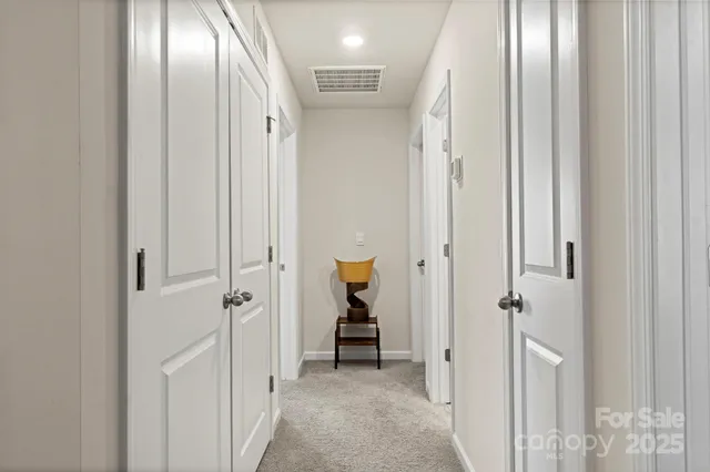 a view of a hallway with wooden floor and a bathroom