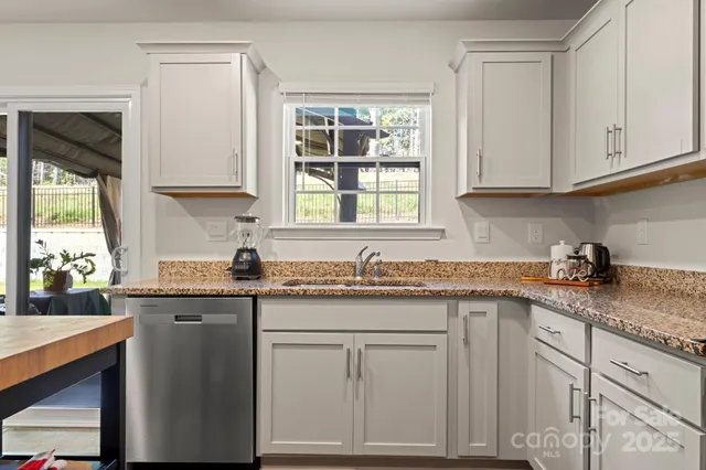 a kitchen with granite countertop white cabinets and window
