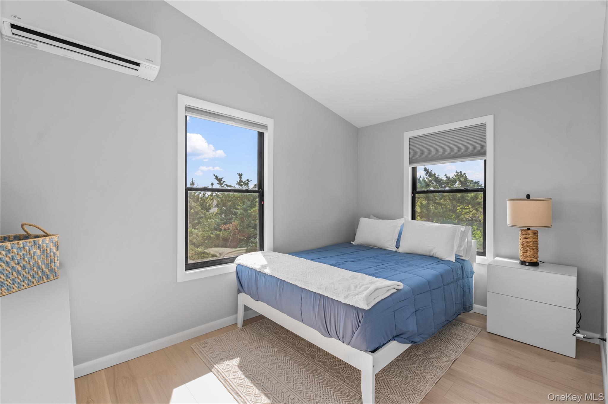 108 Ocean Road Ocean Beach, NY 11770 - Photo 16 of 23 Bedroom with an AC wall unit, vaulted ceiling, light wood finished floors, and multiple windows