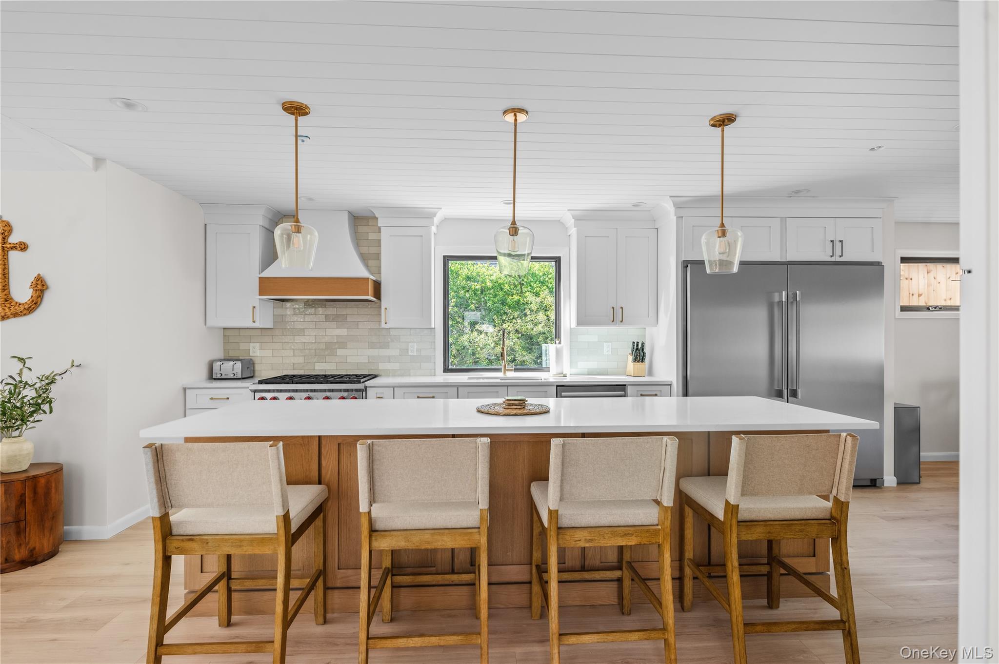 108 Ocean Road Ocean Beach, NY 11770 - Photo 5 of 23 Kitchen featuring decorative backsplash, high end fridge, a kitchen island, light wood-style floors, and a kitchen bar