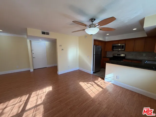 a view of empty room with wooden floor and fan