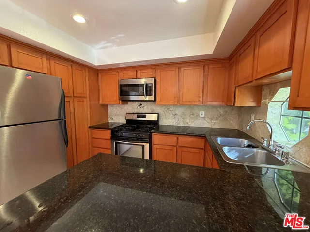 a kitchen with stainless steel appliances granite countertop a refrigerator a stove a sink and a microwave