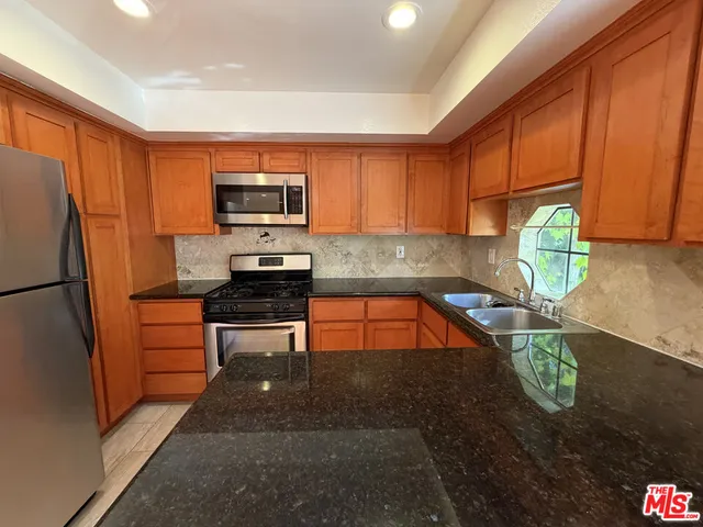 a kitchen with granite countertop a refrigerator sink and stove