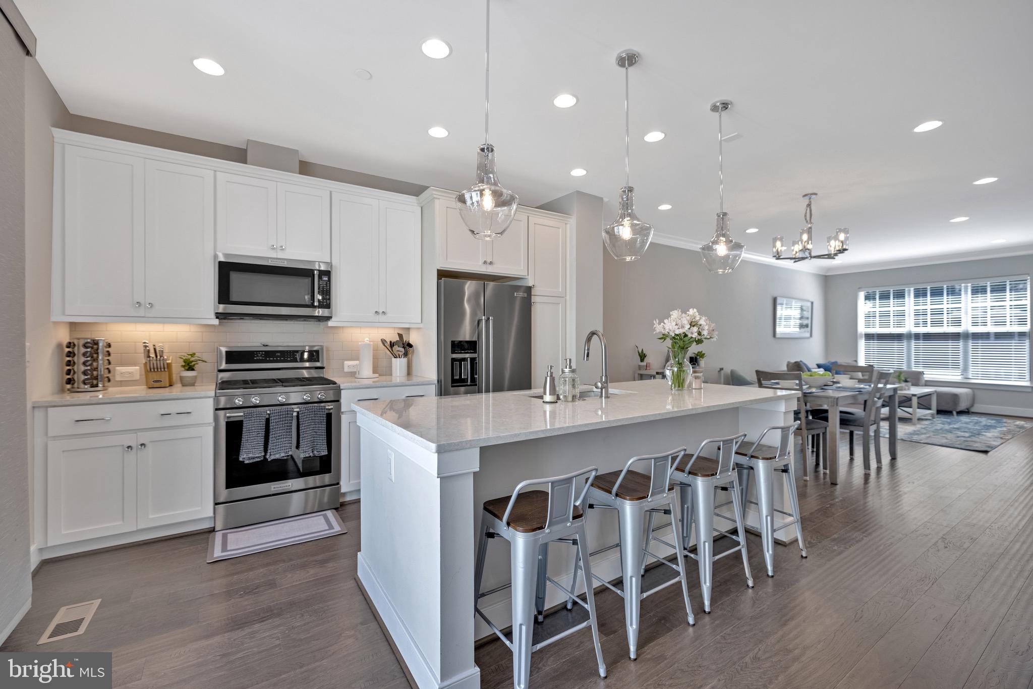 a large kitchen with cabinets chairs and stainless steel appliances