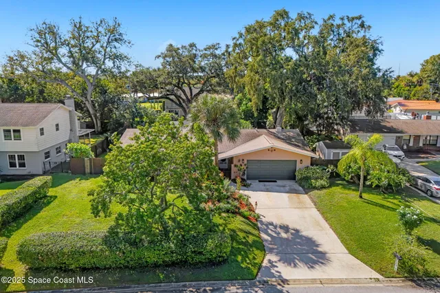 a aerial view of a house with a yard and large trees