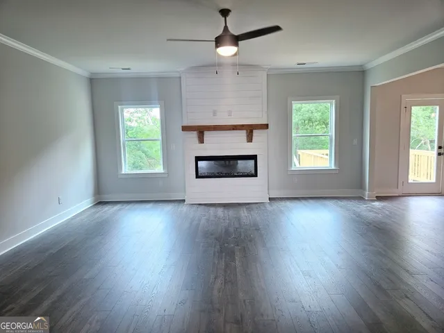 an empty room with wooden floor fireplace and windows