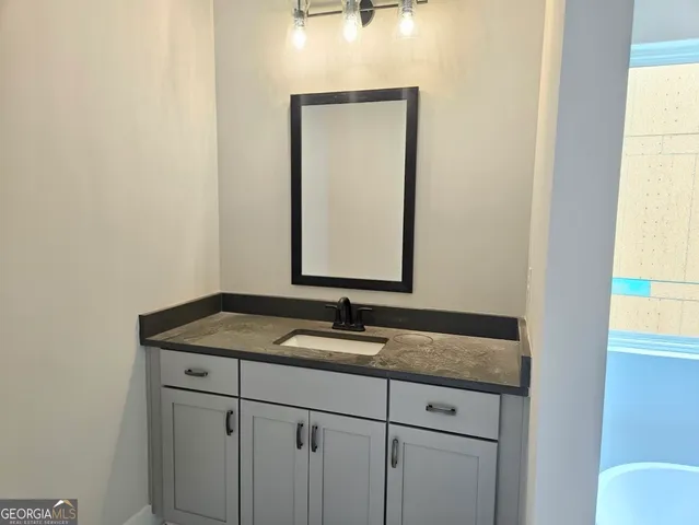 a bathroom with a granite countertop sink and a mirror