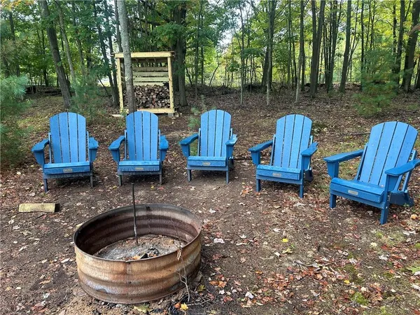 a view of a backyard with table and chairs potted plants and a large tree