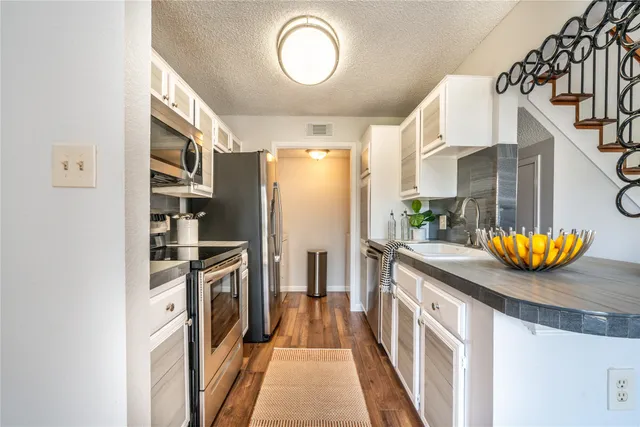 a kitchen with stainless steel appliances granite countertop a sink a stove and a refrigerator