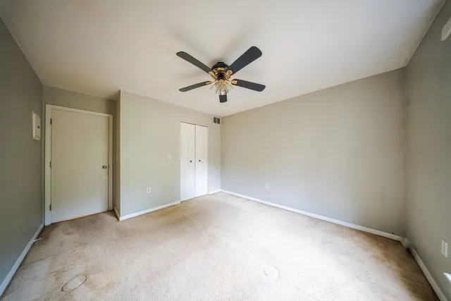 an empty room with windows and fan