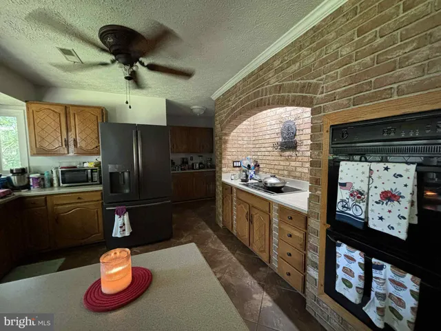 a kitchen with stainless steel appliances granite countertop a refrigerator a sink a stove and a wooden cabinets