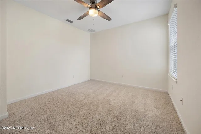an empty room with a window and a fan
