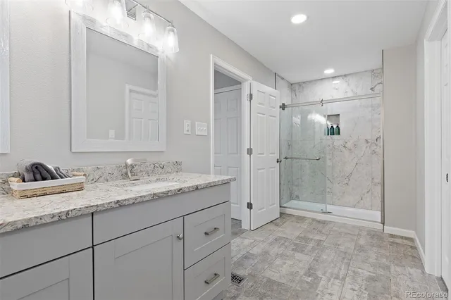 a bathroom with a granite countertop sink mirror and shower