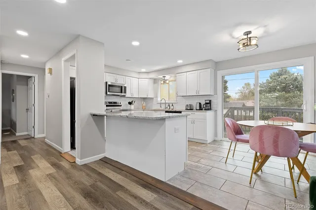 a kitchen with kitchen island a stove a refrigerator and a dining table with wooden floor