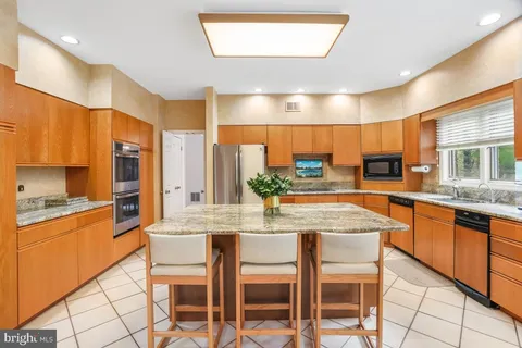 a kitchen with stainless steel appliances granite countertop table chairs sink and cabinets