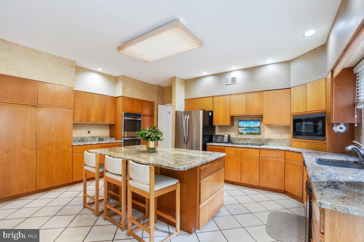 11521 Twining Lane Potomac, MD 20854 - Photo 8 of 31 a kitchen with stainless steel appliances granite countertop a sink and a refrigerator