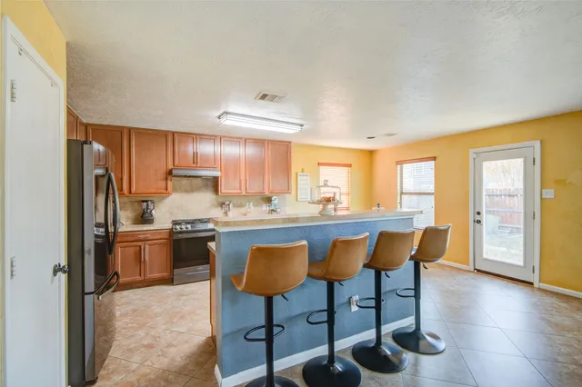 a kitchen with stainless steel appliances granite countertop a stove a refrigerator a sink a dining table and chairs with wooden floor