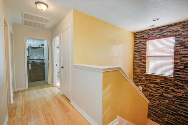 a view of a hallway with wooden floor and a bathroom