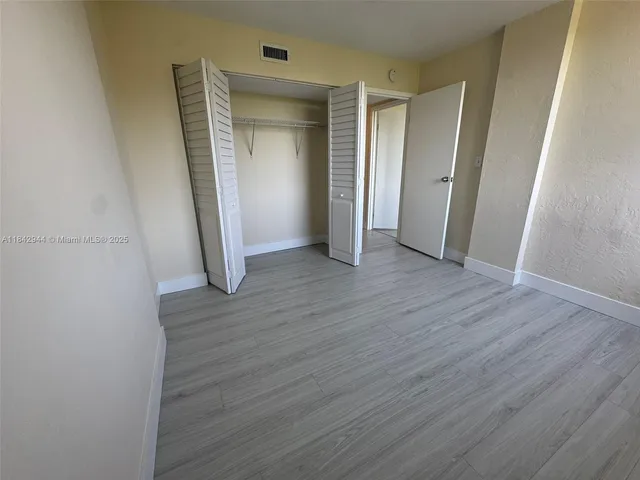 an empty room with wooden floor and closet