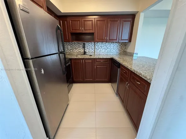 a kitchen with granite countertop a refrigerator a sink and dishwasher