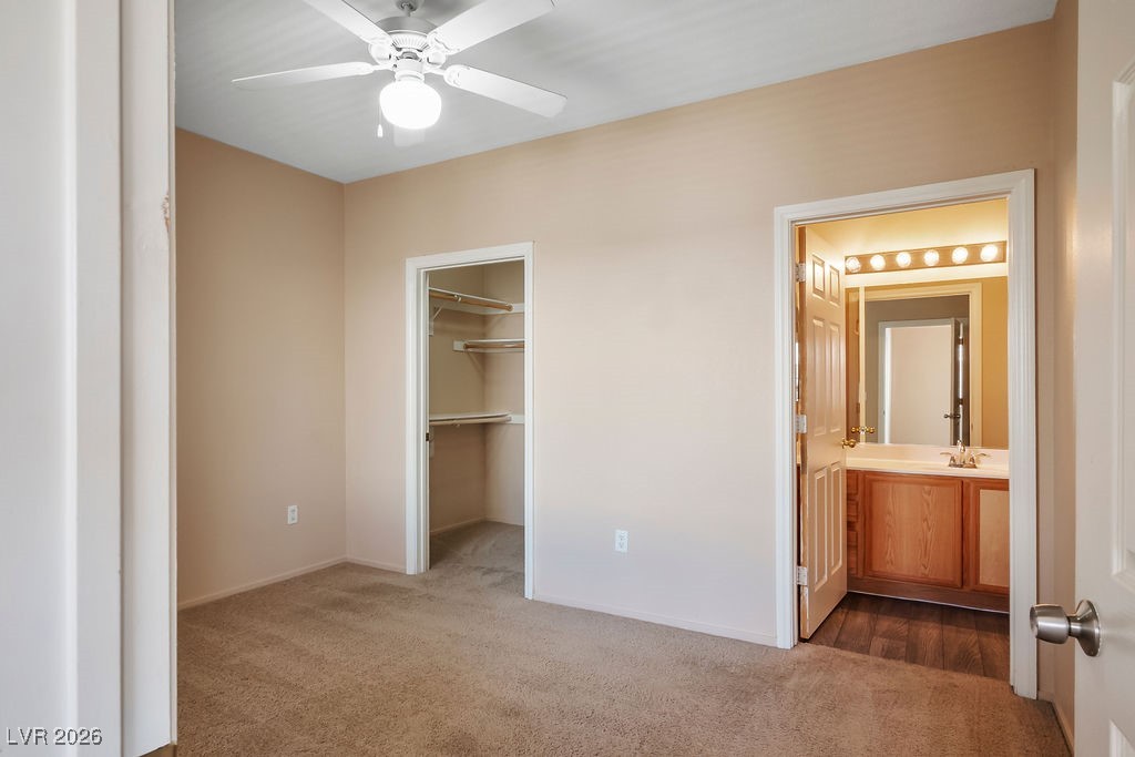 4655 Gold Dust Avenue, Unit 211 Las Vegas, NV 89120 - Photo 12 of 24 Unfurnished bedroom with dark colored carpet, a spacious closet, connected bathroom, and ceiling fan