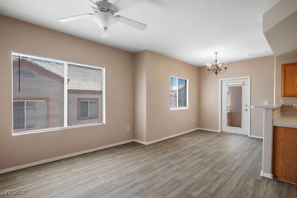 4655 Gold Dust Avenue, Unit 211 Las Vegas, NV 89120 - Photo 2 of 24 Unfurnished dining area featuring light wood-type flooring, a chandelier, and a ceiling fan